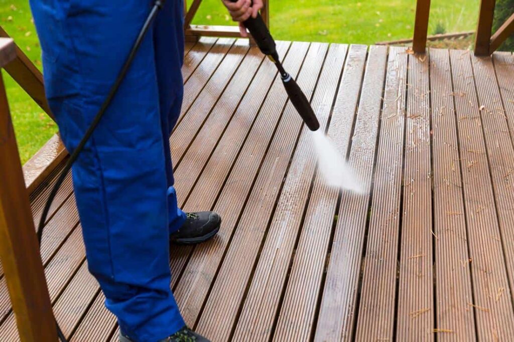 Man pressure washing a deck