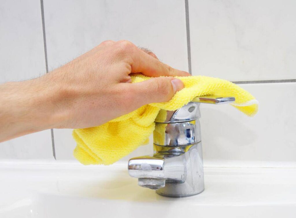 man cleaning a faucet sink