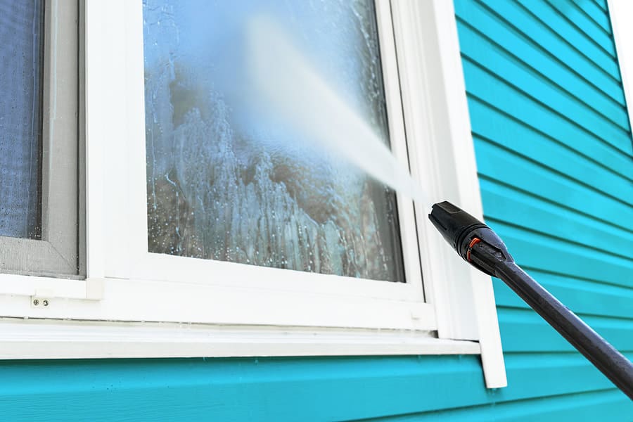 man power washing a window